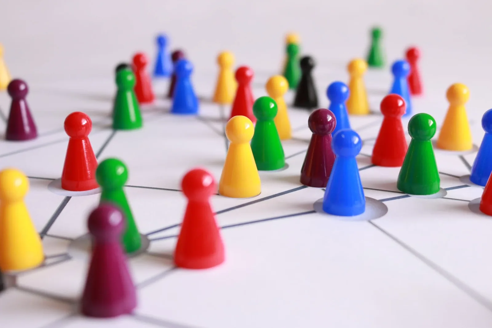 Colored game pawns standing on the points of a network drawn on white paper