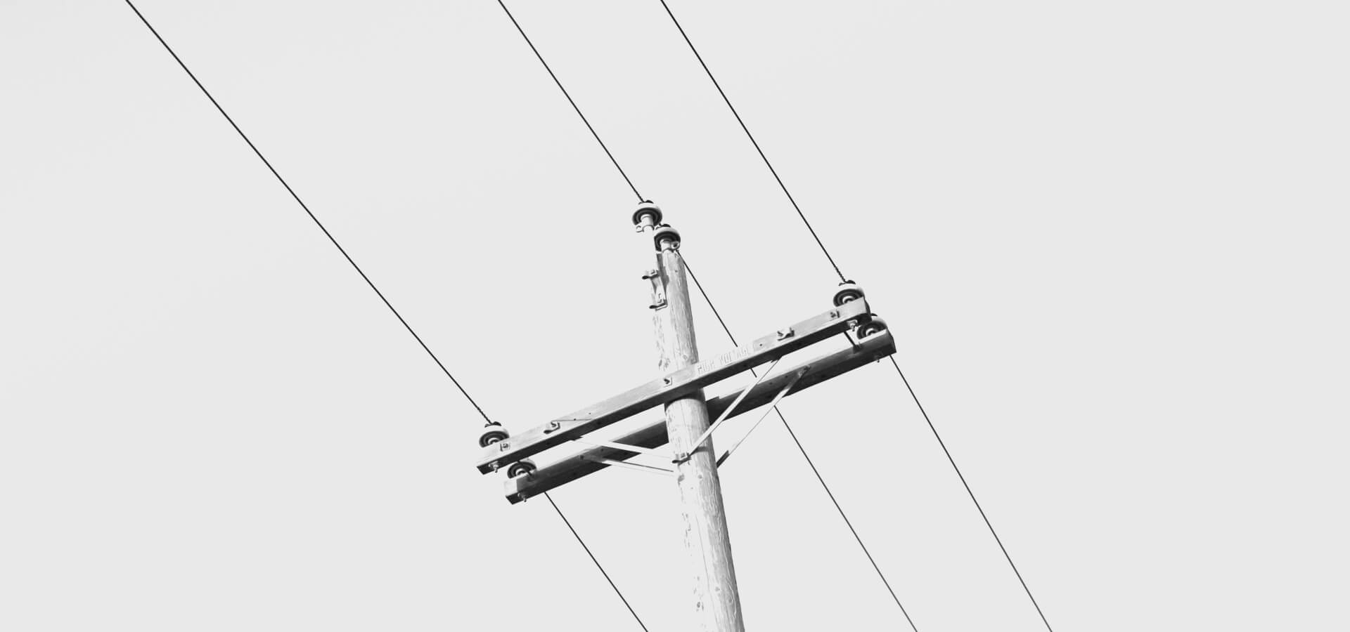 A utility pole carrying power lines against a pale sky
