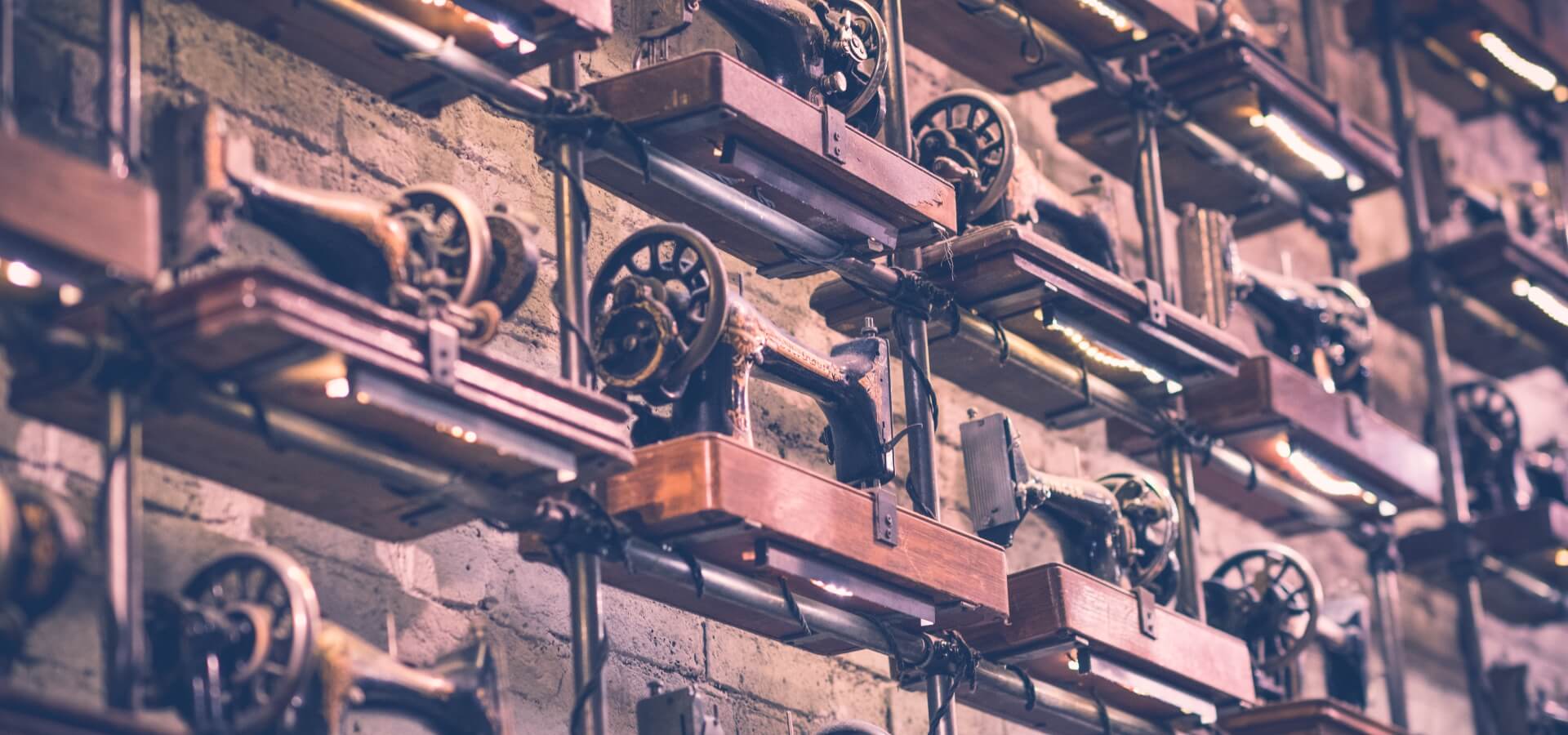Rows of vintage sewing machines mounted on a brick wall